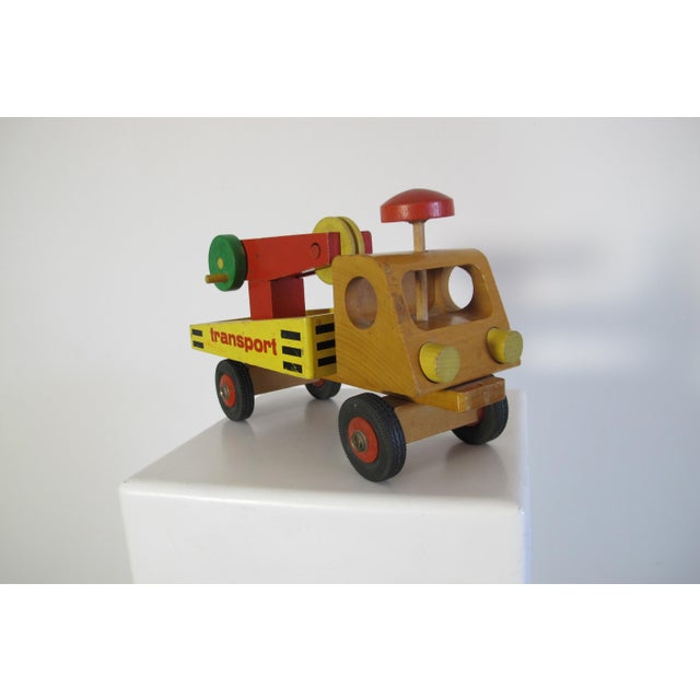This decorative children's toy transport truck is made from wood and rubber and has bright colors.