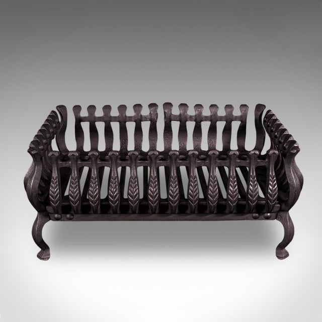 This is an antique fire basket. An English, cast iron fireplace grate dating to the Edwardian period, circa 1905. A...