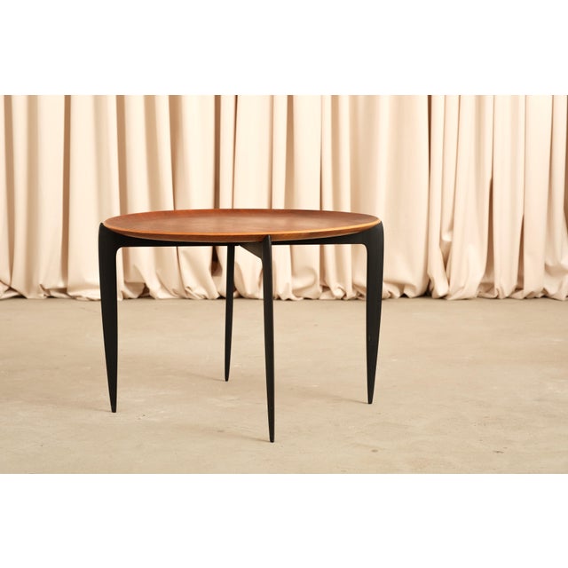 The kind of table that performs a small magic trick: looks like a simple round teak side table, then folds completely flat...
