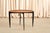 The kind of table that performs a small magic trick: looks like a simple round teak side table, then folds completely flat...