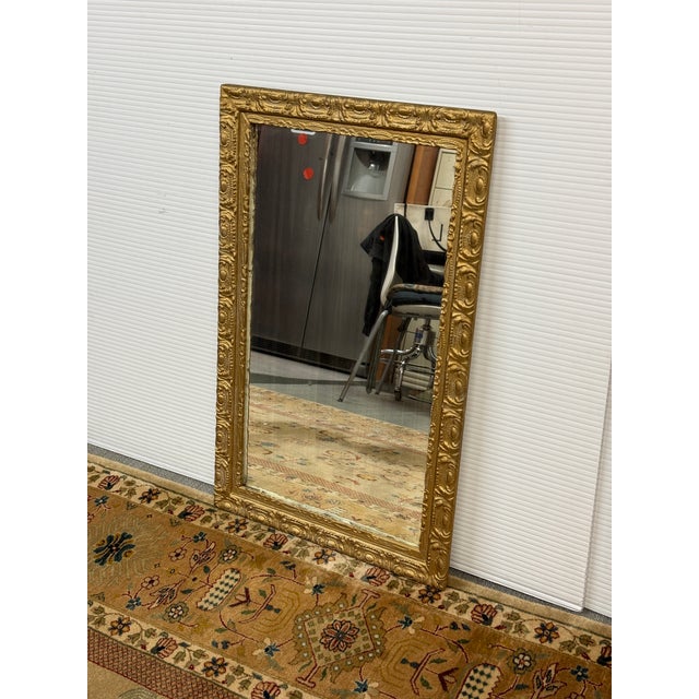Design Plus Gallery presents a Gilt Wood Wall Mirror in Gold. The beveled edge mirror is inset in a heavy carved frame...