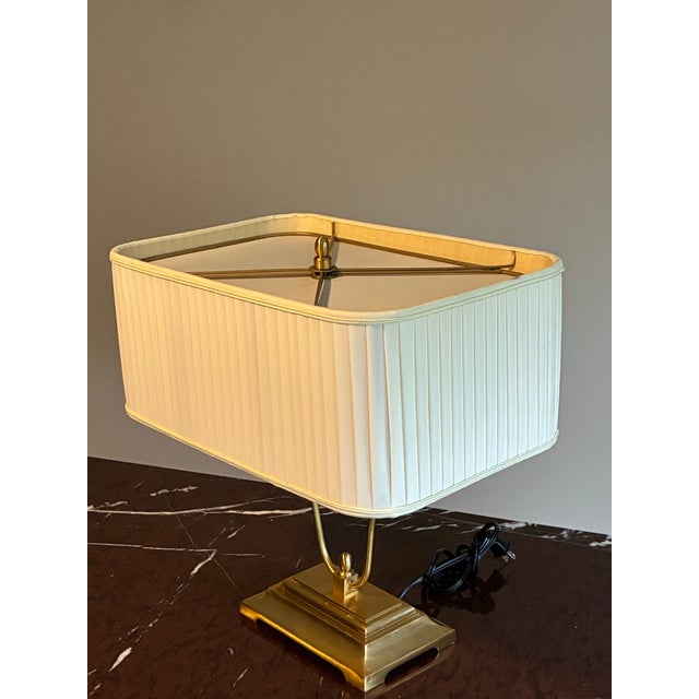 Elegant attributed Baker table lamp featuring a sculptural solid brass form with refined Neoclassical lines and a...