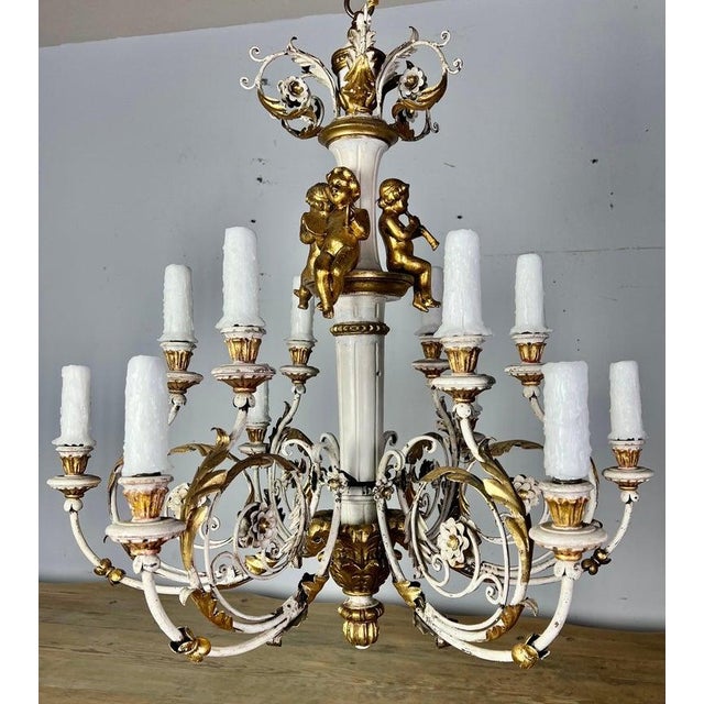 Italian twelve light painted & parcel gilt Rococo style chandelier with carved wood cherubs. The fixture is made of iron &...