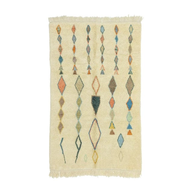 Playful hand-knotted wool rug featuring a Cream base with Pastel teal, Taupe, Peach, Blue Sky, Muted Orange, and Olive...