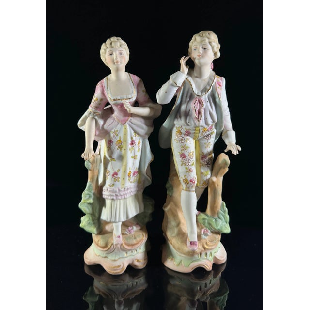 A pair of Arnart Creations bisque porcelain French style figures. Numbered 7955 with four feather crossed arrow marks. The...