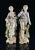 A pair of Arnart Creations bisque porcelain French style figures. Numbered 7955 with four feather crossed arrow marks. The...
