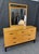 This Mid-Century Modern maple dresser features a clean, linear design with eight drawers accented by sleek black pulls....