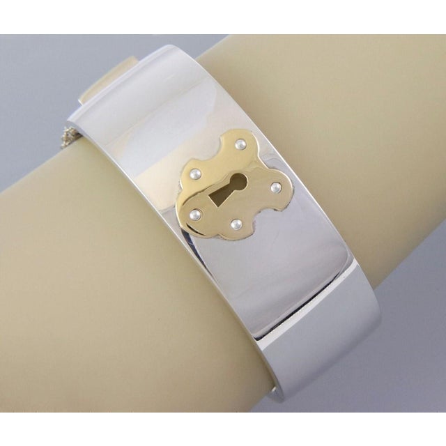 Discover the elegance of Tiffany & Co with this sterling silver and 18k gold wide key lock bangle bracelet. Crafted with a...