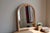 Arched portrait-style wall mirror with a molded frame tinted in an elegant powder pink. Its design of repeated fluting and...