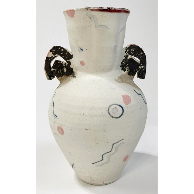 Unique vintage studio pottery vase. Features matte ivory white base with black handles to each side and hand-painted Pop...