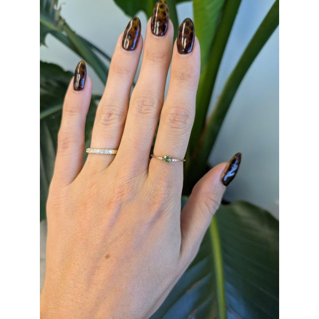 A rare demantoid garnet glows in a vivid, fiery green at the center of this solid 14K rose gold ring, flanked by four...