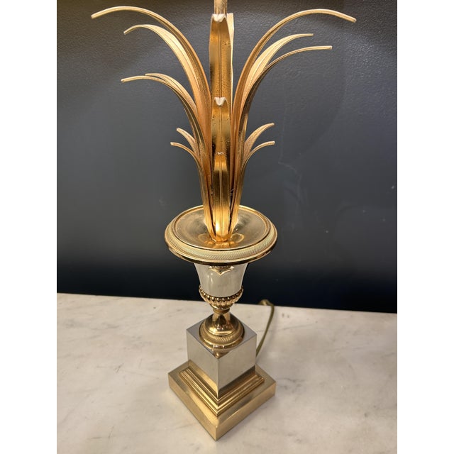 Pair of chromed metal table lamps with truncated conical vase-shaped stems, topped with a sheaf of gilt brass palm leaves....