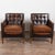 20th century pair of vintage leather club chairs featuring button-tufted backs, decorative nailhead trim, and self-piped...