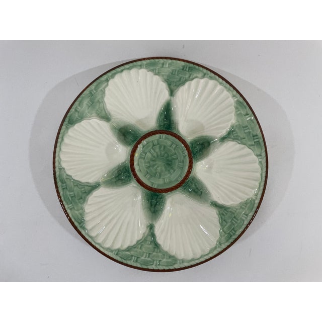 A charming French Faience Longchamp glazed majolica oyster plate with a lighter green basket weave background trimmed with...