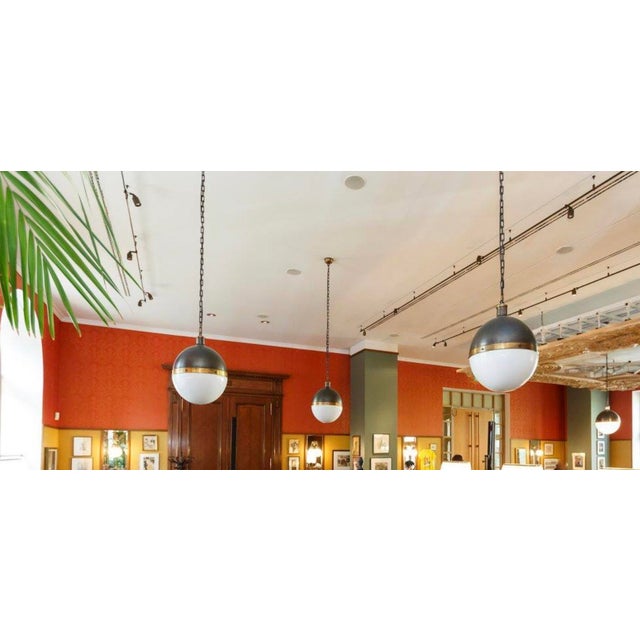Large Hicks ball pendant light designed by Thomas O'Brien, New York, bronze with hand-rubbed antique brass and milk glass...