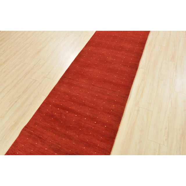 A contemporary Gabbeh runner hand-knotted with an all-wool pile on a cotton foundation. This oriental rug features an all-...