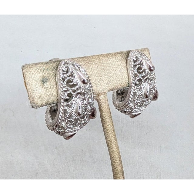 1960s rhodium plated filigree with raised tear drop shapes half hoop clip earrings. Marked crown "TRIFARI©" on the clips....
