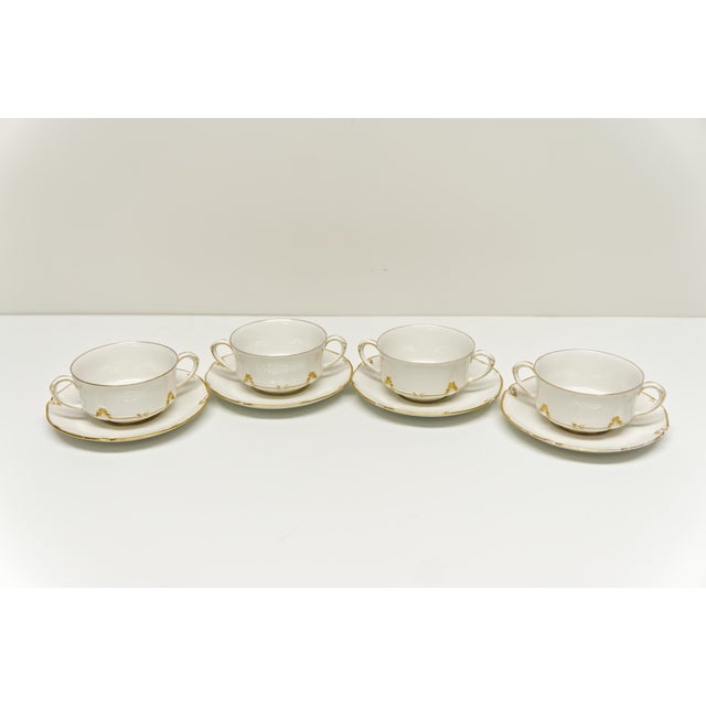 A set of 4 porcelain bouillon cups with matching saucers by CH Field Haviland Limoges featuring a gold ivy trim and gold...