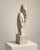 An evocative late-20th-century sculpture depicting two elongated, interlocking faces in a quiet embrace. The abstracted...