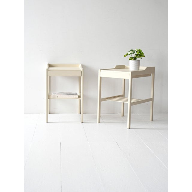 Vintage 1950s white lacquered nightstands with a hidden drawer and a slatted lower shelf. Pair of original 1950s...