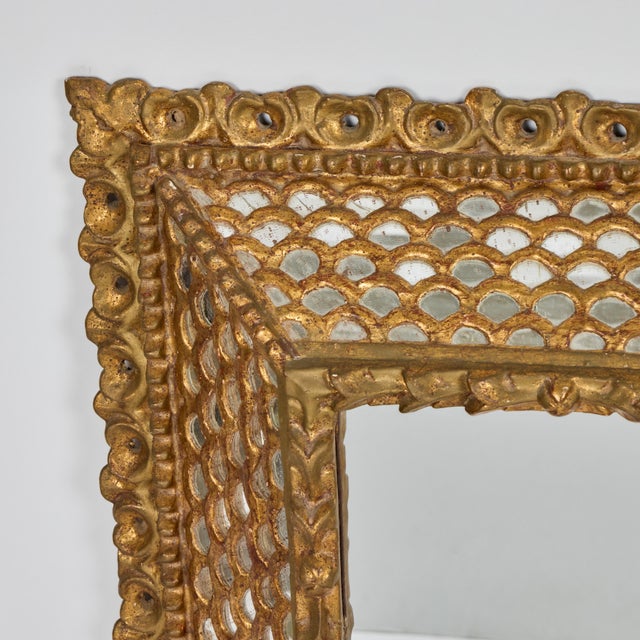 A striking Spanish Colonial-style giltwood mirror from the 1920s, richly detailed with layered craftsmanship and warm,...