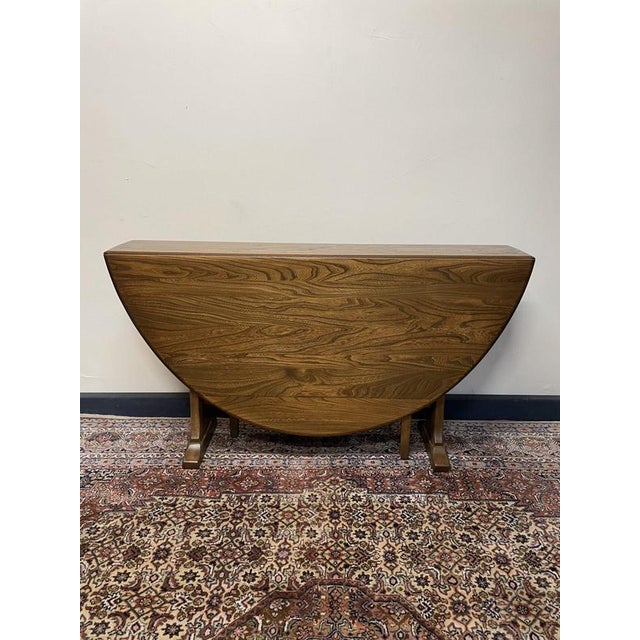 A sophisticated mid-century dining table by Ercol, renowned for their exceptional craftsmanship. Expertly crafted from...