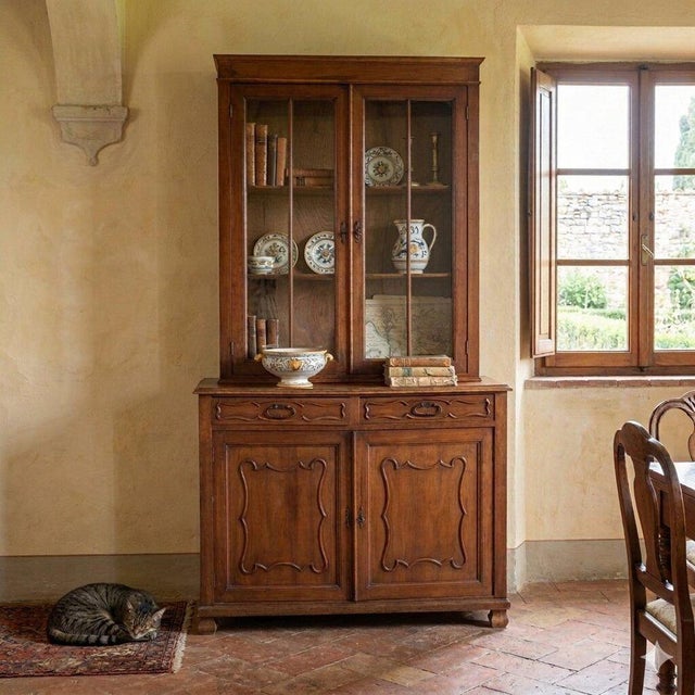 Walnut veneered sideboard. Upper part with glass doors and two internal shelves, base with a pair of paneled doors topped...