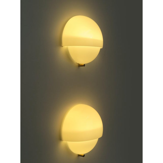 Mania wall lamps designed by Vico Magistretti for Artemide in 1963, model with white opaline Murano glass with a Vetri...