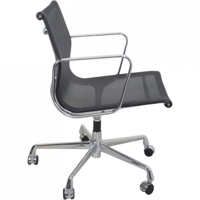 Charles Eames EA-117 office chair upholstered in black mesh, with chrome armrests and frame. The chair is from 2002 and...
