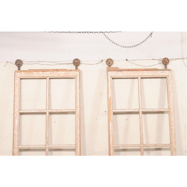A French tall pair of glass paneled sliding doors, retaining their original overhead iron roller hardware, from the early...