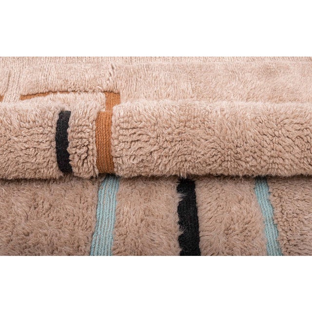 Artistic hand-knotted wool rug in Warm Sand, highlighted with geometric lines in Midnight Black, Ginger Honey, and Arctic...