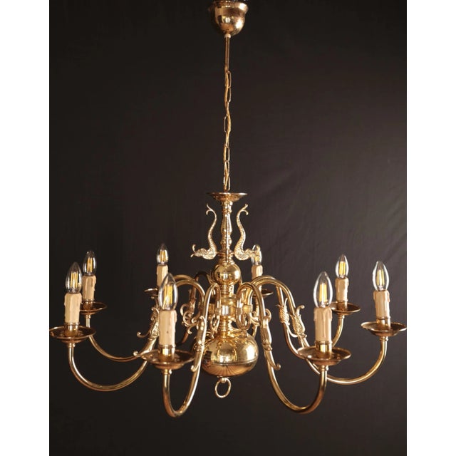 Beautiful eight-armed flemish chandelier made of polished brass. The upper part of the chandelier is decorated with fish....