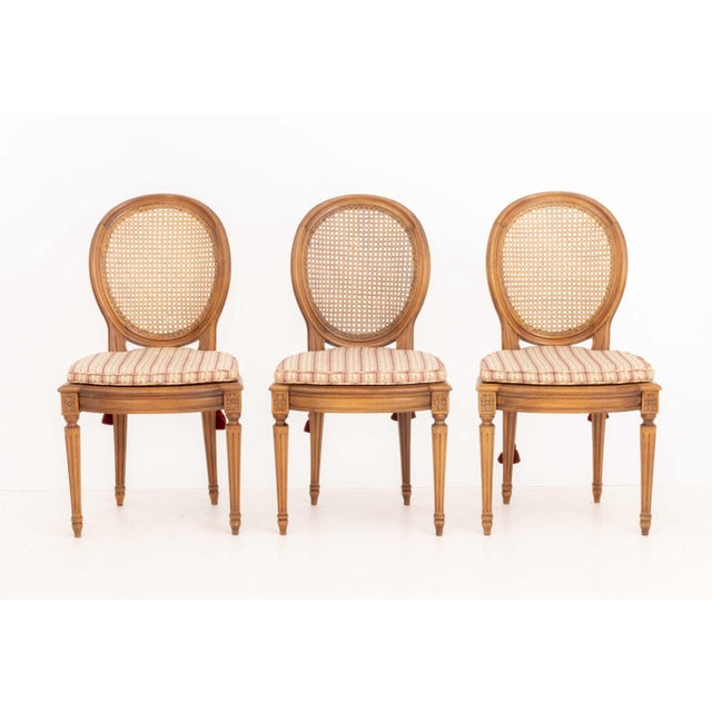 Set of Six Louis XVI Style Cane-Paneled Walnut Dining Chairs, each with striped fabric upholstered cushion above fluted...