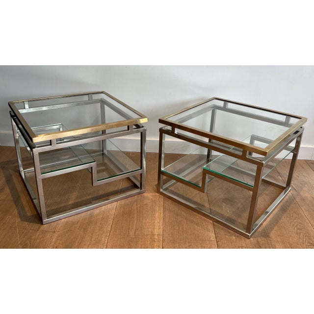 This beautiful pair of designer side tables is made of chrome, brass, and glass. It is a French work. Circa 1970
