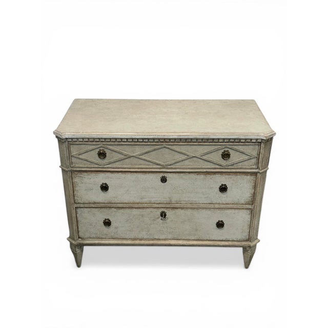 A pair of Gustavian chests of drawers in gray. The tops are finished in a lighter shade of gray, providing a subtle...