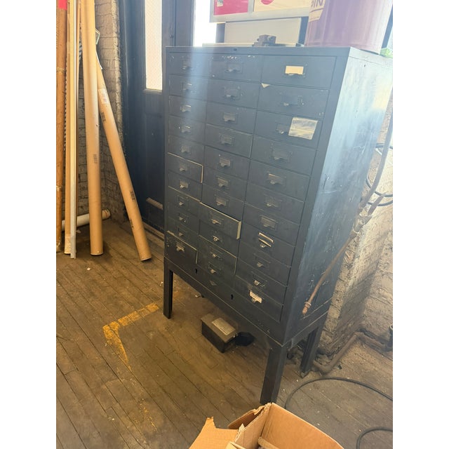 This vintage industrial apothecary cabinet features a bank of small metal drawers perfect for organizing tools, hardware,...