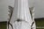 An American white ceramic table lamp from the 1940s, featuring sculptural leaf motifs that wrap around the tapered body...