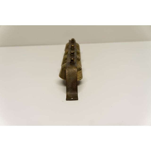 Four antique brass carriage sleigh bells mounted on a sturdy metal bracket, featuring a warm aged patina and classic...