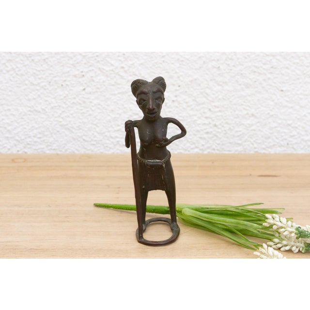 Invite the captivating artistry and cultural heritage of Africa into your home with this intriguing bronze figure of a...