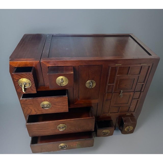 A striking two-piece puzzle tansu cabinet, crafted in solid elmwood and inspired by traditional Japanese Edo–Meiji period...