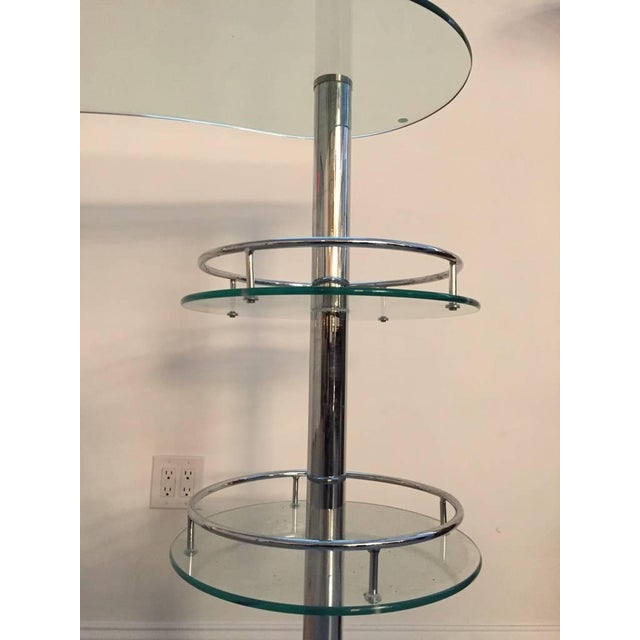 Mid Century Modern chrome and glass dry bar. Having three-tiers for bottles and glassware. Along with a curved glass top.