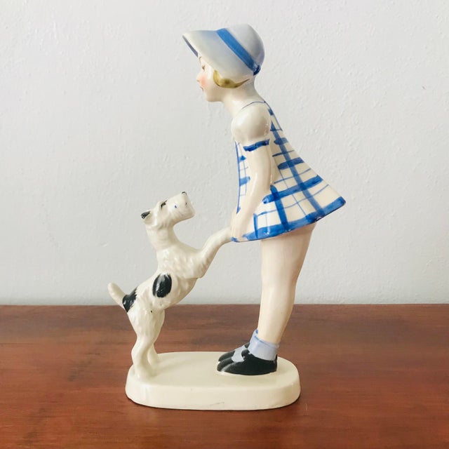 This vintage porcelain figurine, featuring a young girl with her playful Schnauzer or Airedale dog, is a delightful piece...