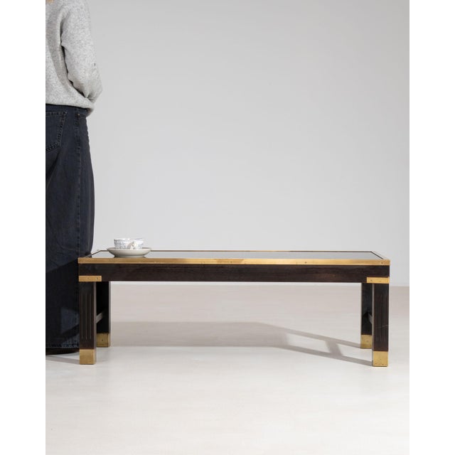 A distinctive mid-century coffee table featuring a glass top enclosing a sculptural relief motif, complemented by wood and...