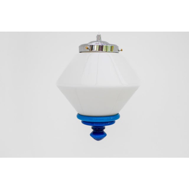 A striking Swedish Art Deco pendant milk glass lamp with striking blue details, produced in the 1930s, exemplifying the...