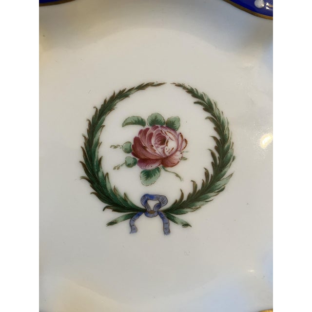 A Ginori porcelain dish with singular pink rose surrounded with laurel “wreath” tied with bow. Dish is trimmed with cobalt...