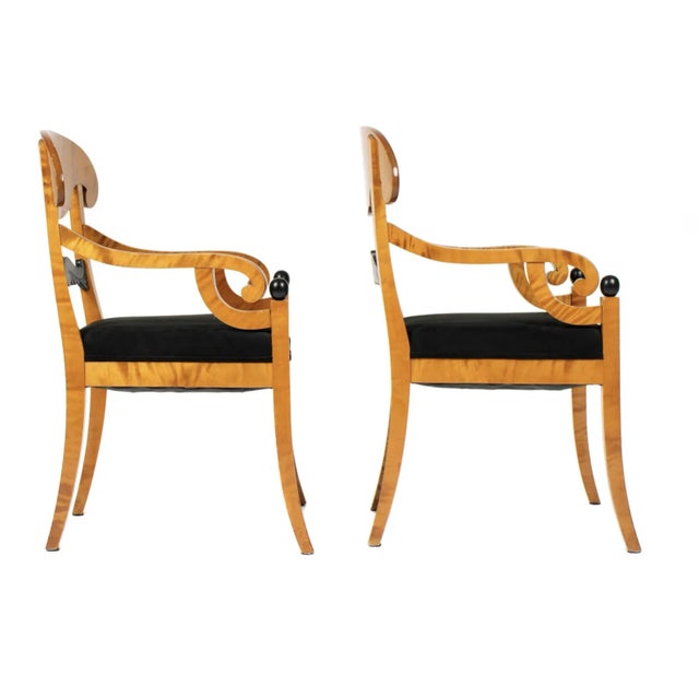 A Pair of Biedermeier Style Arm Chairs. Chairs feature birch frames, shaped top rail over carved ebonized back splat, arms...