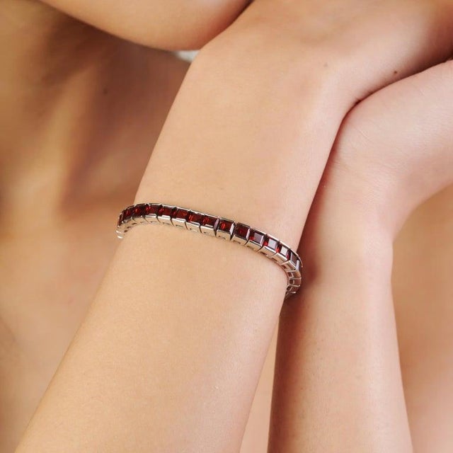 This elegant tennis bracelet is crafted in 925 sterling silver and beautifully set with 43 natural garnet gemstones, each...