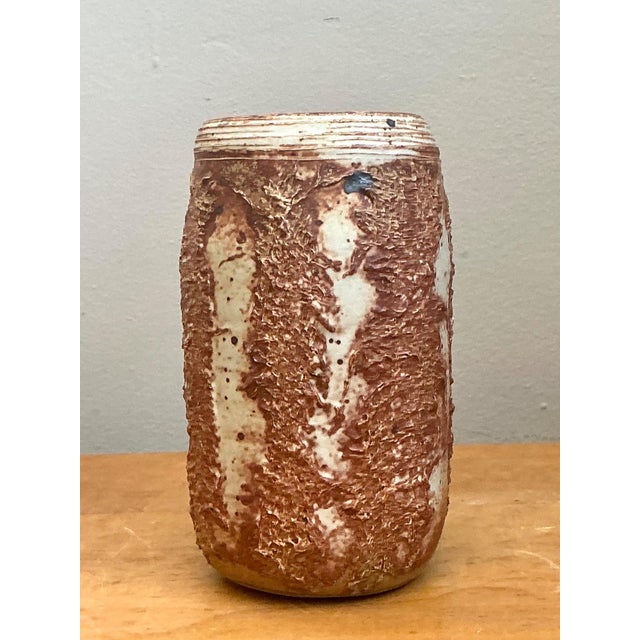 This vintage studio pottery vase is a compelling example of mid-century craftsmanship, defined by its rich earthy palette...
