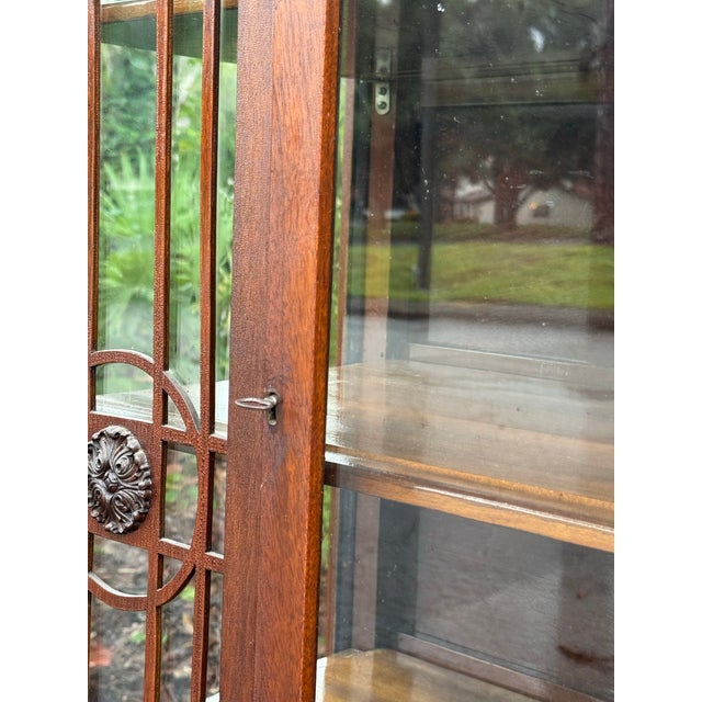 A timeless antique mahogany curio cabinet dating to circa the 1930s, featuring rich reddish-brown wood tones, elegant...