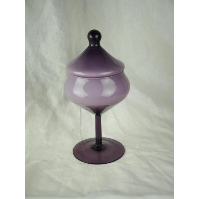 Empoli glass candy jar on amethyst-colored base. This impressive jar has a shape that can recall classic motifs and which...